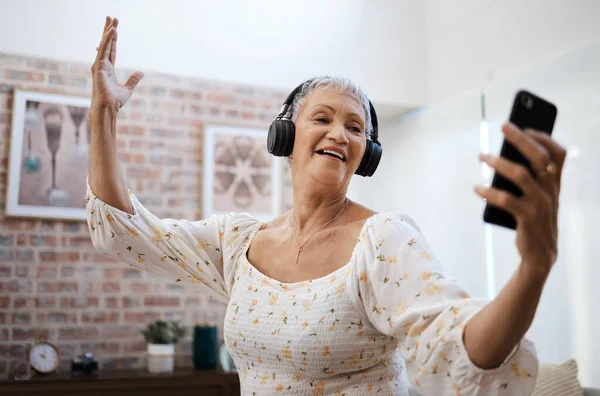 青春的泉源充满了欢乐 在家里用智能手机和耳机跳舞的老年妇女 — 图库照片