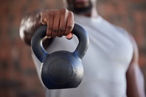 Fitness, bodybuilder and black man kettlebell training, exercise or workout for powerful arm strength at gym. African, hand and strong sports athlete bodybuilding or weightlifting in a health club.