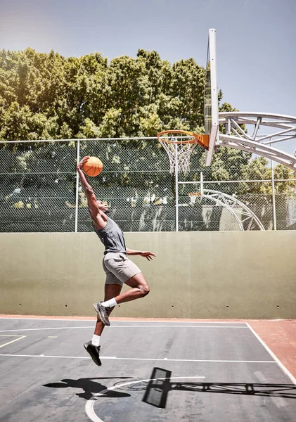 Basketball, sports and jump with man on court playing games for fitness, training and health. Energy, exercise and workout with basketball player in outdoor for wellness, summer and athlete lifestyle.