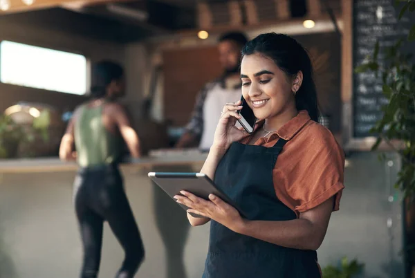 Let me read that order back to you. an attractive young woman standing outside her restaurant and using technology to take orders