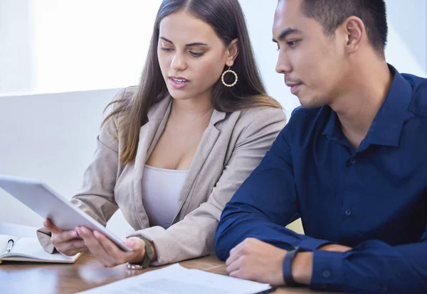 Using practical business tools to gain an edge. two businesspeople using a digital tablet together in an office