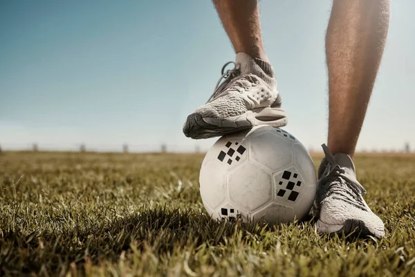 Soccer, ball and shoes in sport motivation on grass for training, exercise and fitness in the outdoors. Legs of football player standing for healthy sports workout, practice or game on a green field.