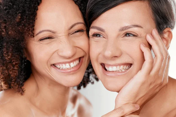 Wow Your skin feels amazing. two beautiful mature women posing against a grey background in studio