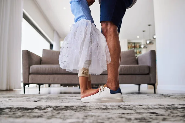 Feet, dance and girl dancing with father in a living room, love and family fun in their home together. Shoes, happy family and parent teaching child dancer, loving and caring support by single dad.