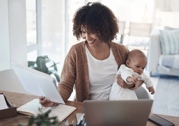 Making the balancing act look like a breeze. a young woman using a laptop while caring for her adorable baby girl at home