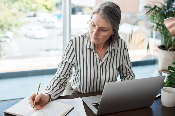 m a shark, yall jus codfish. a mature businesswoman making notes in a modern office