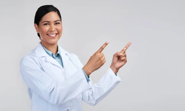 Scientifically proven to get your name out there. Cropped portrait of an attractive young female scientist pointing towards copyspace in studio against a grey background