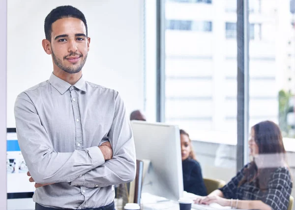 My team and I can assist you. Portrait of a young businessman standing in an office with his colleagues in the background