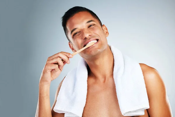 Dental, health and man use toothbrush and toothpaste to clean teeth for healthy mouth, gums and happy. Confident, male and relax shows oral hygiene with big smile, cleaning and brushing teeth.