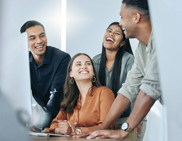 Make time to laugh with your team. a diverse group of businesspeople standing together in the office and using a computer