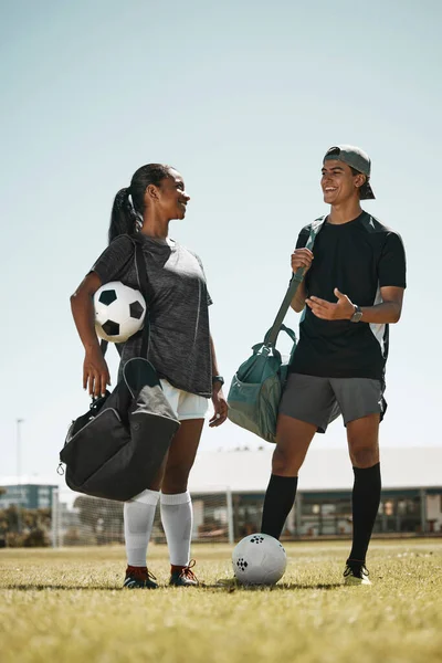Soccer ball, woman or man on grass field after fitness, training or exercise for competition game or match. Smile, happy or talking football players, sports people or team after energy health workout.