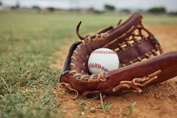 Baseball, ball and glove on an outdoor pitch for sport training, fitness or a tournament game. Exercise, sports equipment and softball match on a professional field or stadium with grass and sand