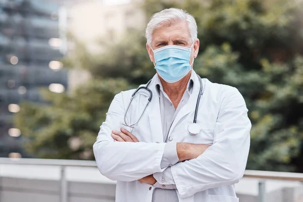 Get serious about wearing your mask. a mature male doctor standing with his arms crossed in the city