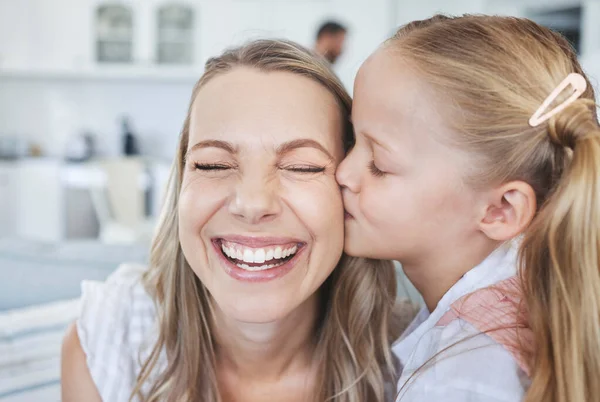 Girl, mother and kiss on cheek for love, happiness and bonding together in family home. Woman, smile and child kissing on face for mothers day, birthday and happy in house with kid, care and time.
