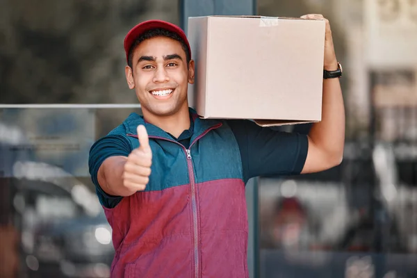 Thumbs up, courier man and delivery package from ecommerce online shopping store. Happy young friendly retail shipping worker, customer cargo box and thank you or well done support hand sign.