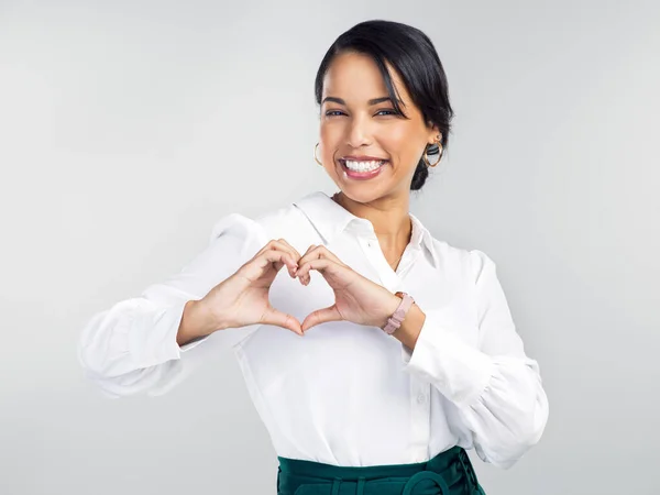 A big heart brings big success. Studio shot of a young businesswoman making a heart shaped gesture with her hands against a grey background