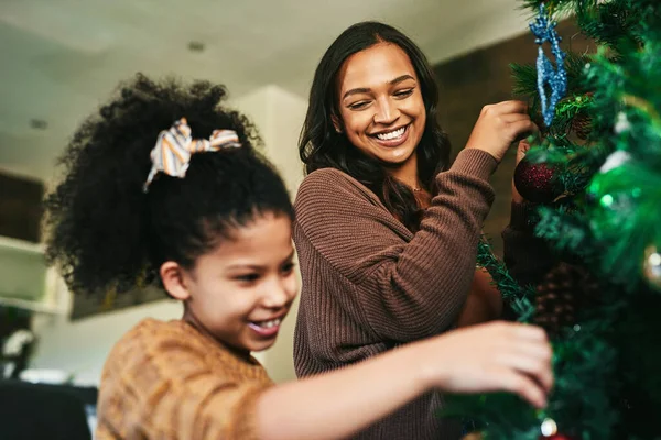 Just mommy and me trimming the tree. a happy young mother and daughter decorating the Christmas tree at home