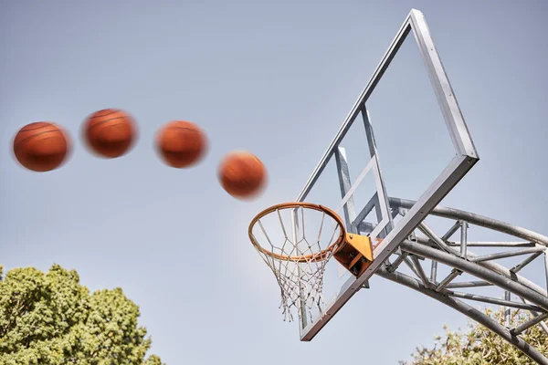 Basketball, point and ball in basket for winning score on basketball court in park with summer sky. Game, sports goals and training practice with motion, action and motivation for winner shot in hoop.