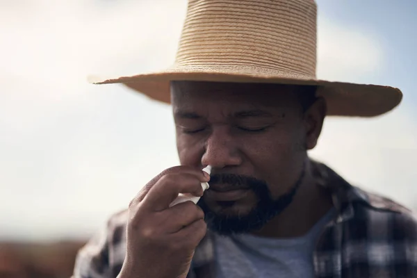 春になるとアレルギーが立ち上がります 農場で働きながら鼻スプレーを使う成熟した男は — ストック写真