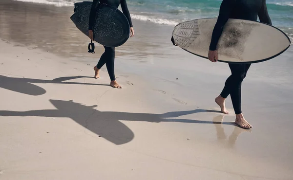 波が呼んでいる ビーチを歩いている間にサーフボードを持っている2人は — ストック写真