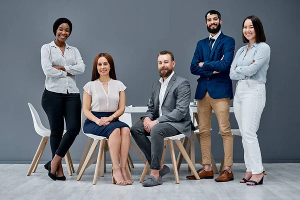 Watch us bring success to our team yet again. Portrait of a group of businesspeople posing together against a grey background