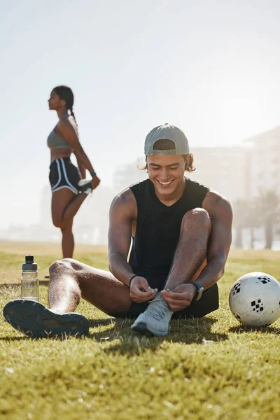 运动和健身 用足球在草地上伸展 在公园里为运动和户外运动热身 年轻男子系鞋带 黑人女子和体格健康的运动训练 — 图库照片