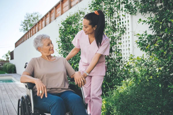 Filled heads with no regrets. a young nurse caring for an older woman in a wheelchair