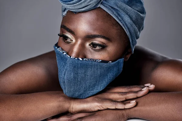 Beauty can still shine through, despite half of your face being covered. a beautiful young woman wearing a denim head wrap and mask