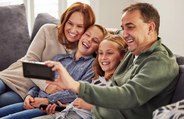 一起把握最美好的时刻一个快乐的家庭一起坐在家里的沙发上 用手机自拍 — 图库照片
