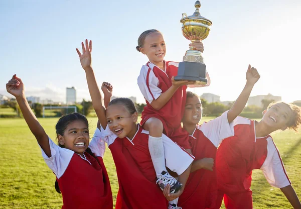 Trophy, winner and football children with success, winning and excited celebration for sports competition or game on field. Happy soccer girl kids team with motivation, celebrate winning achievement.