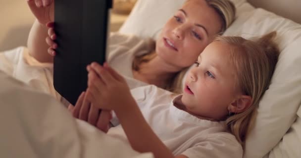 当一个女孩和一个母亲躺在卧室里观看或流媒体系列的订阅服务时 你可以用平板电脑 床和放松一下 爱情和子女与妇女和女儿在家里结合在一起 — 图库视频影像
