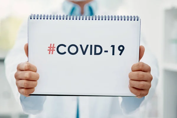 The one thing we dont want to be trending. a scientist holding a sign with COVID-19 on it in a modern laboratory