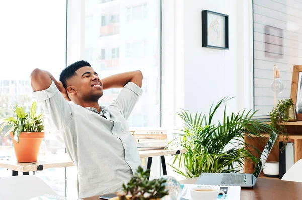 When you work hard you deserve every reward. a young businessman relaxing at his desk in a modern office