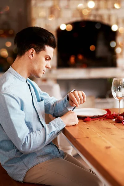 I dont think that shes showing up. a man checking the time while waiting for his date at a dining table