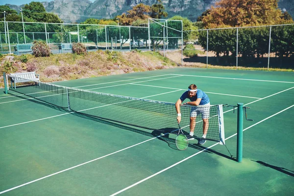 当其他一切似乎都失败时 冠军仍在继续 一名年轻的男性网球选手在室外网球场上无精打采地打网球的全景镜头 — 图库照片