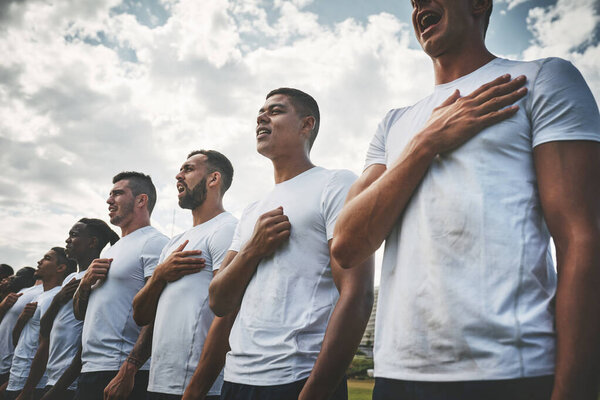 Its an emotional time. a team of confident young rugby players standing at attention singing their anthem outside on a field before a rugby match