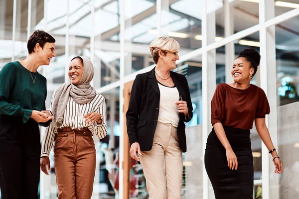 Walking into the office as a group of go-getters. a group of businesswomen walking alongside each other in an office