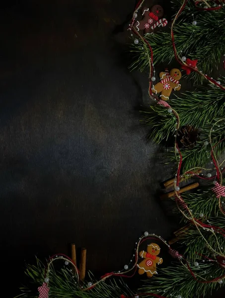 Koyu ahşap arka planda Noel ağacının yeşil dalları ve Noel oyuncakları