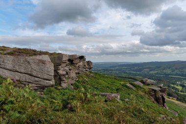 Bamford Edge manzaralı mavi gökyüzü, tüylü bulutlar ve mor fundalarla Umut Vadisi boyunca bakıyor. Derbyshire, Peak District Ulusal Parkı.