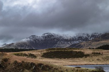 Kuzey Galler 'deki Snowdonia Ulusal Parkı' nda kış boyunca Llyn y Dywarchen, Snowdon ve Y Garn 'ın panoramik manzarası.