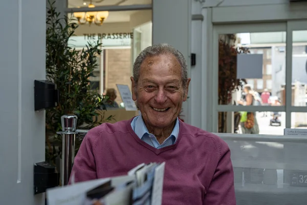 Mature male senior citizen looking happy, and cheerful in a city centre cafe.