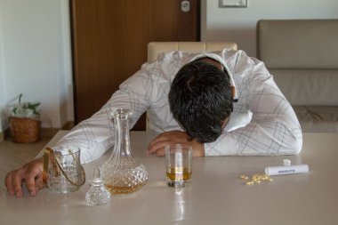 Alkol ve psikotropik uyuşturucu kullandıktan sonra evdeki masada uzanan bir adam..