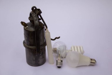 Image of an old lantern, a candle and light bulbs. Evolution of light in the home