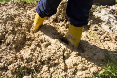 Sarı çizmeli bir adamın bacakları çamura battı..