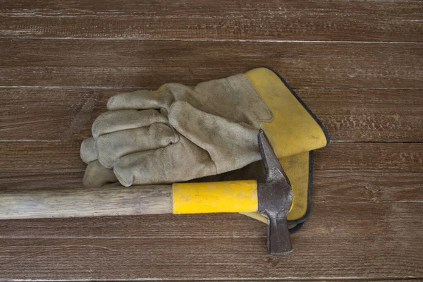 Bir çift iş eldiveni ve çekiç resmi. Ağır iş ve olası yaralarının bir göstergesi.