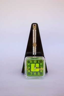 Bir masa saati ve metronomun resmi. Geçen tampona ve ölçümüne referans ver