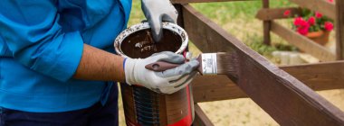 Ev çitlerini boyayan becerikli bir adamın elleri. Kendin yap ahşap koruma işi. Yatay Pankart