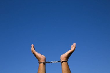 Tutuklandıktan sonra bileklerinde kelepçe olan bir adamın elleri. Özgürlüğe referans