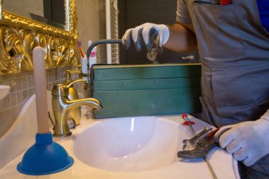 Ellerinde lavaboyu tıkayan bir tutam saç tutan iş eldivenli bir tesisatçının elleri. Ev işlerini kendin yap.