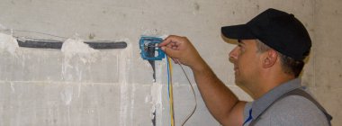 Tamirci bir elektrikçinin inşaat alanındaki korugonun içinden elektrik sondasını geçirdiği görüntü. Bir evin elektrik sisteminin farkına varmak. Yatay Pankart 